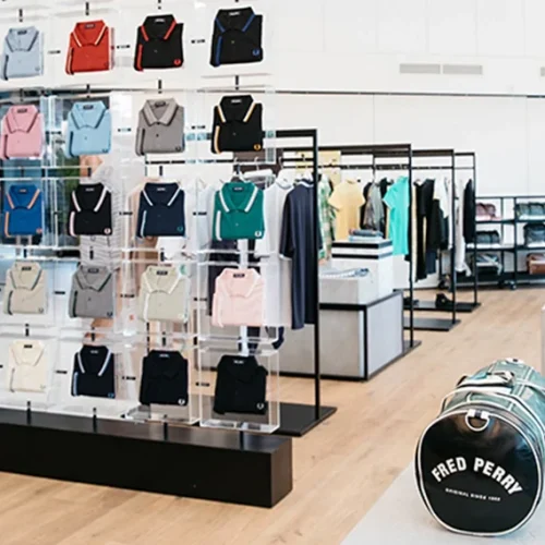 Tienda de ropa con expositores cuadrados de metacrilato transparente con ropa suspendida